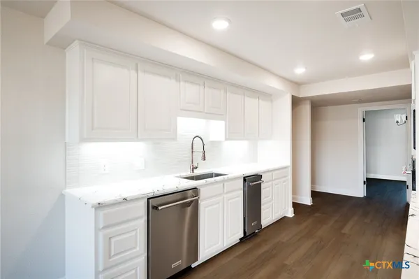 a view of an empty room with wooden floor and a ceiling fan
