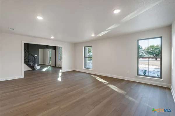 a view of an empty room with wooden floor fireplace and a window