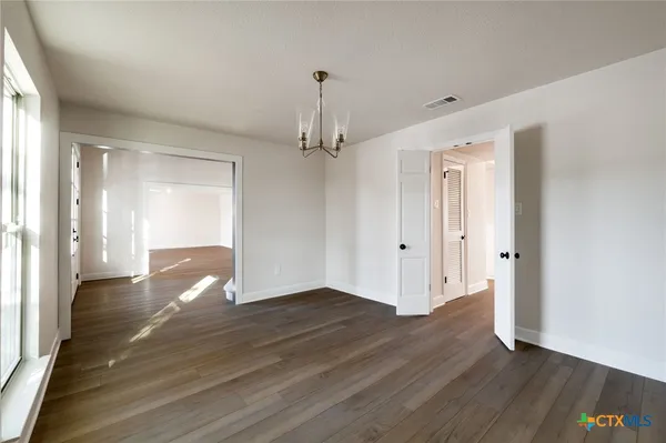a view of an empty room with wooden floor and a ceiling fan