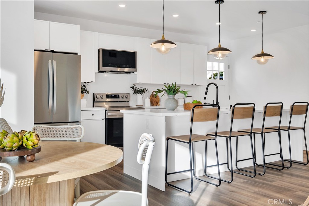 226 A Arena Street El Segundo, CA 90245 - Photo 20 of 47 a kitchen with stainless steel appliances granite countertop a stove a sink a dining table and chairs with wooden floor
