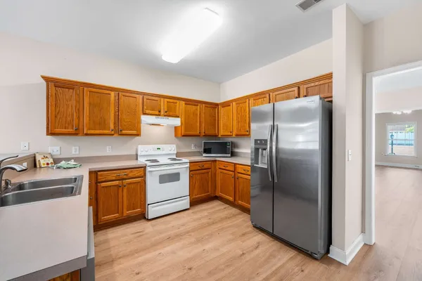 a kitchen with stainless steel appliances granite countertop a refrigerator a microwave oven cabinets and a wooden floor