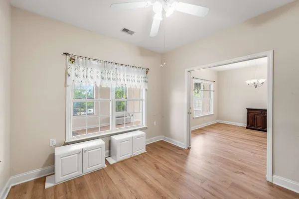 a view of an empty room with wooden floor fridge and a window