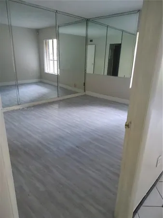 an empty room with wooden floor and mirror