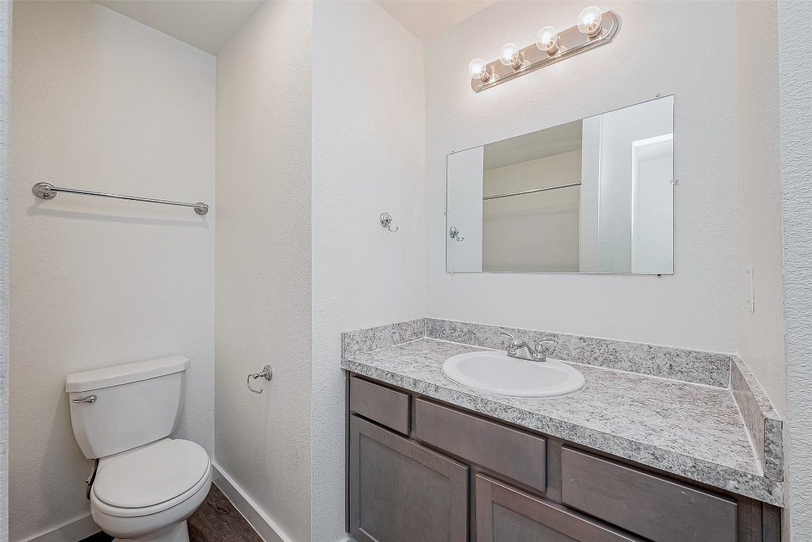 21155 Gosling Road, Unit 15 AB Spring, TX 77388 - Photo 12 of 30 This bathroom features a modern vanity with a granite countertop, a single sink, and a large mirror. It has a neutral color palette, a standard toilet, and a towel bar. The room is well-lit with a sleek light fixture above the mirror.