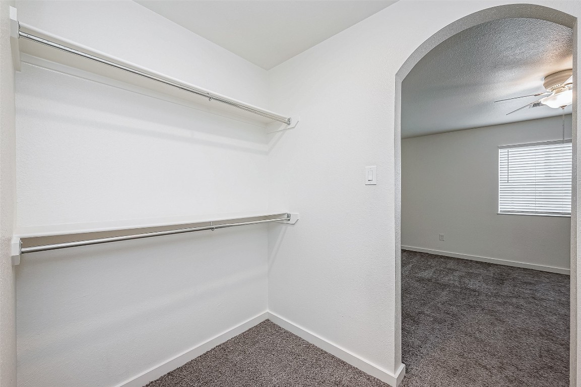 21155 Gosling Road, Unit 15 AB Spring, TX 77388 - Photo 22 of 30 This photo shows a spacious walk-in closet with white walls, two hanging rods, and carpeted flooring. It includes a wall-mounted electrical panel, suggesting utility connections.