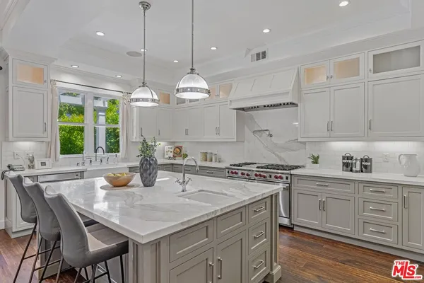 a kitchen with a stove a sink a center island and cabinets