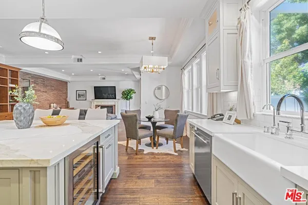 a open kitchen with stainless steel appliances granite countertop a sink dishwasher and a dining table with wooden floor