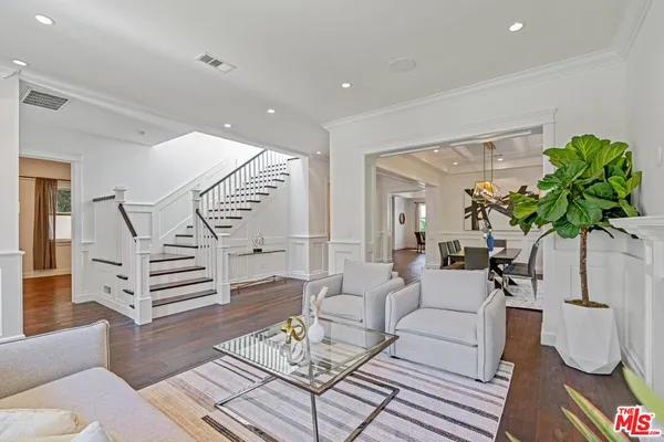 a living room with furniture flowers and wooden floor