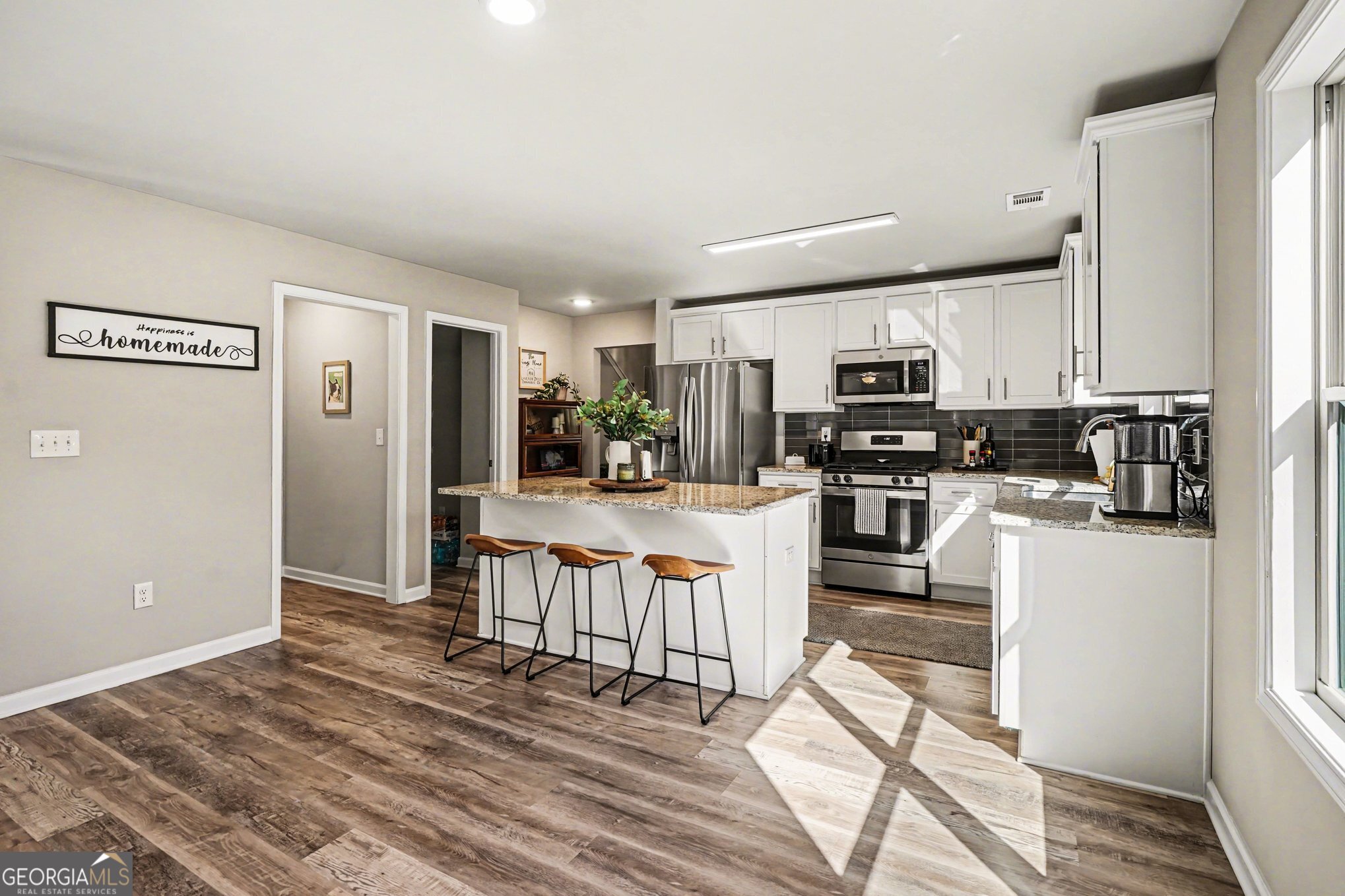 994 Lakeview Drive Commerce, GA 30529 - Photo 12 of 42 a kitchen with stainless steel appliances kitchen island granite countertop a refrigerator oven a sink a dining table and chairs with wooden floor
