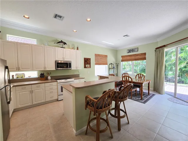 a kitchen with stainless steel appliances granite countertop a stove top oven a sink dishwasher a dining table and chairs with wooden floor