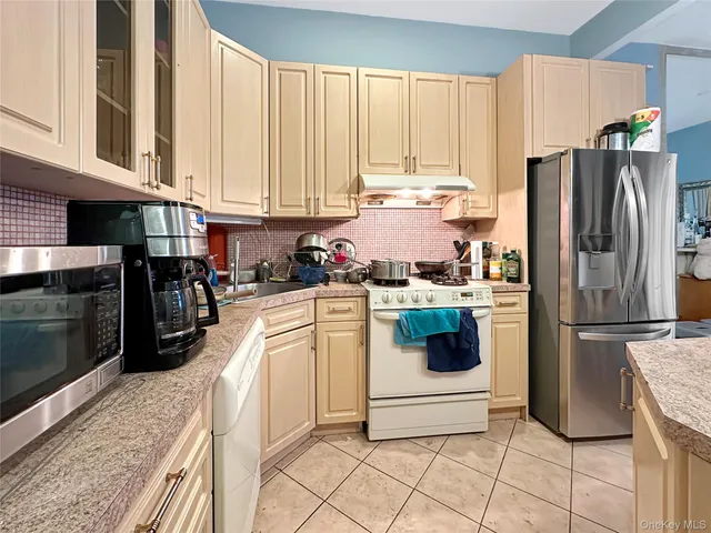 a kitchen with a refrigerator and white cabinets