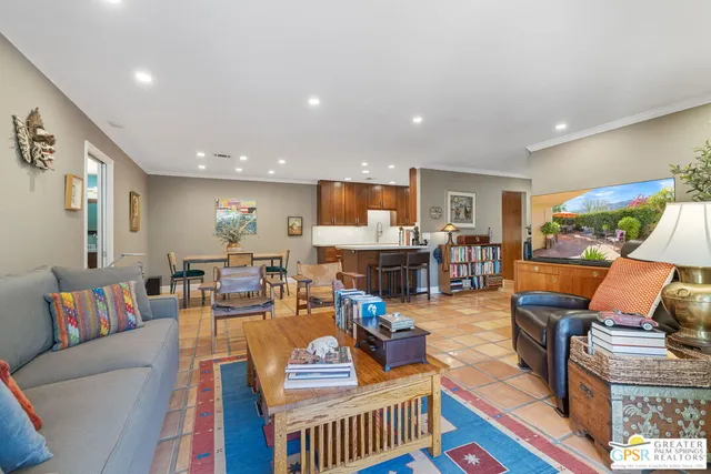 a living room with furniture kitchen view and a large window