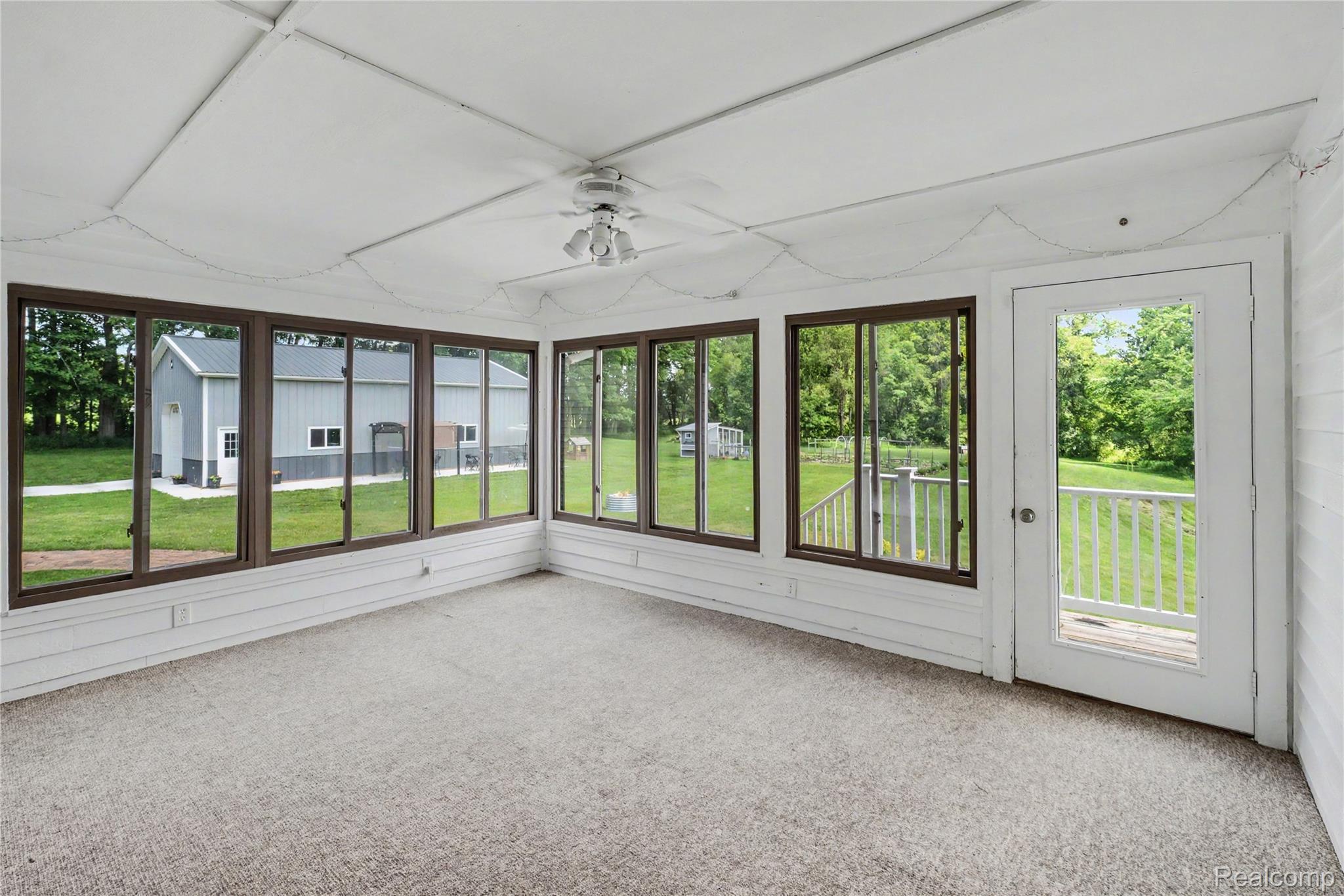 5465 South Lake George Road Metamora, MI 48455 - Photo 20 of 61 Sunroom with large windows, carpeting, ceiling fan, white paneled walls, glass-paneled door onto deck w/white railings