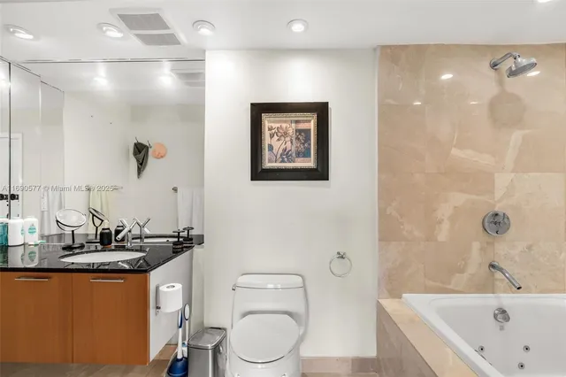 a bathroom with a granite countertop sink a toilet and shower