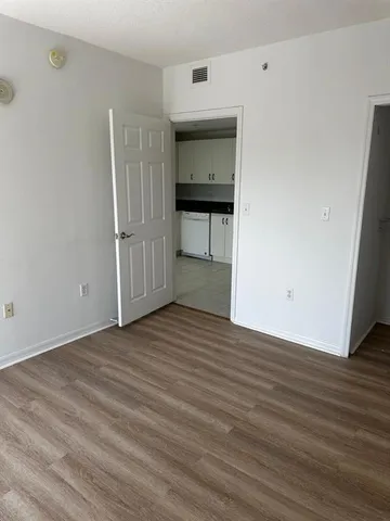 a view of an empty room with wooden floor and cabinet