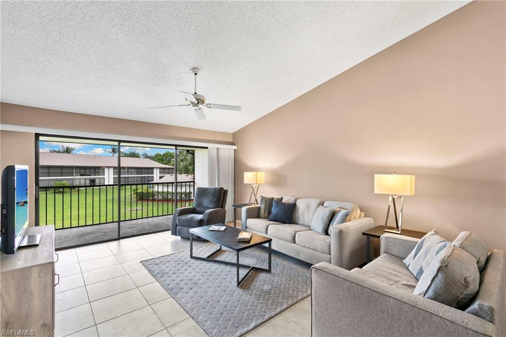 236 Pebble Beach Circle, Unit A202 Naples, FL 34113 - Photo 4 of 25 a living room with furniture and a floor to ceiling window