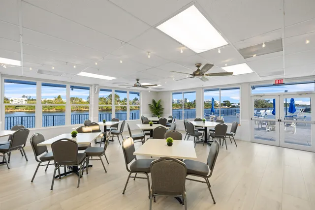 a room with lots of tables a large window and chairs