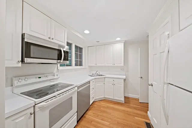 a kitchen with white cabinets and white appliances