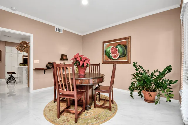 a dining room with furniture potted plants and a kitchen view