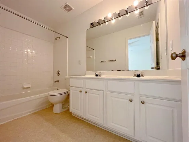 a bathroom with a double vanity sink a toilet and a bathtub