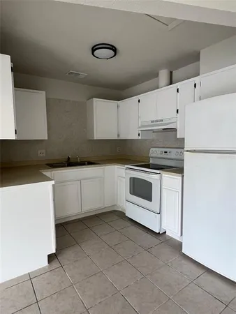 a white kitchen with granite top and white stainless steel appliances