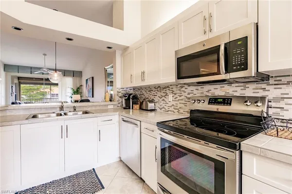 a kitchen with stainless steel appliances a stove a sink a microwave a dining table and chairs