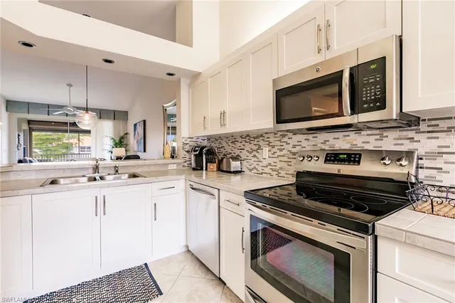 a kitchen with stainless steel appliances a stove a sink a microwave a dining table and chairs