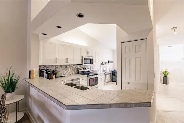 a kitchen with stainless steel appliances granite countertop a stove top oven a sink a dining table and chairs