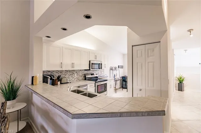 a kitchen with stainless steel appliances granite countertop a stove top oven a sink a dining table and chairs