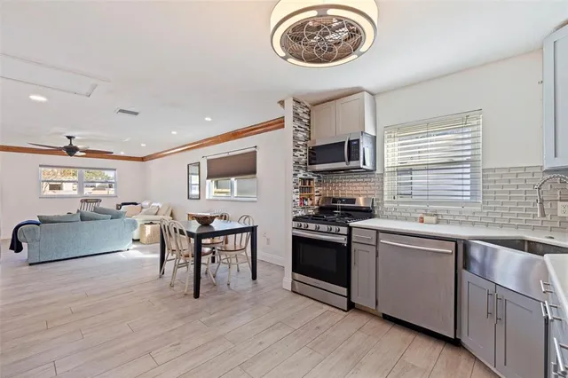 a kitchen with stainless steel appliances granite countertop a stove top oven a sink dishwasher a dining table and chairs with wooden floor