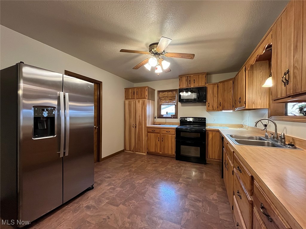 5295 Deer Road Southwest Bowerston, OH 44695 - Photo 10 of 39 Kitchen with black appliances, brown cabinetry, light countertops, and a sink