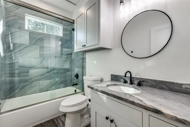 a bathroom with a granite countertop toilet a sink and a mirror