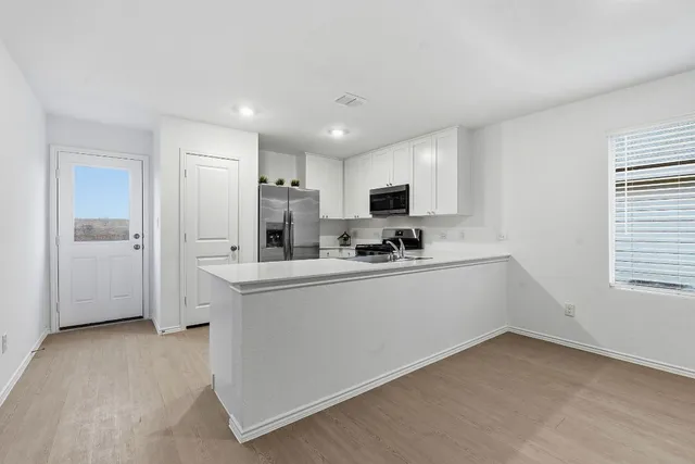 a kitchen with white cabinets and window
