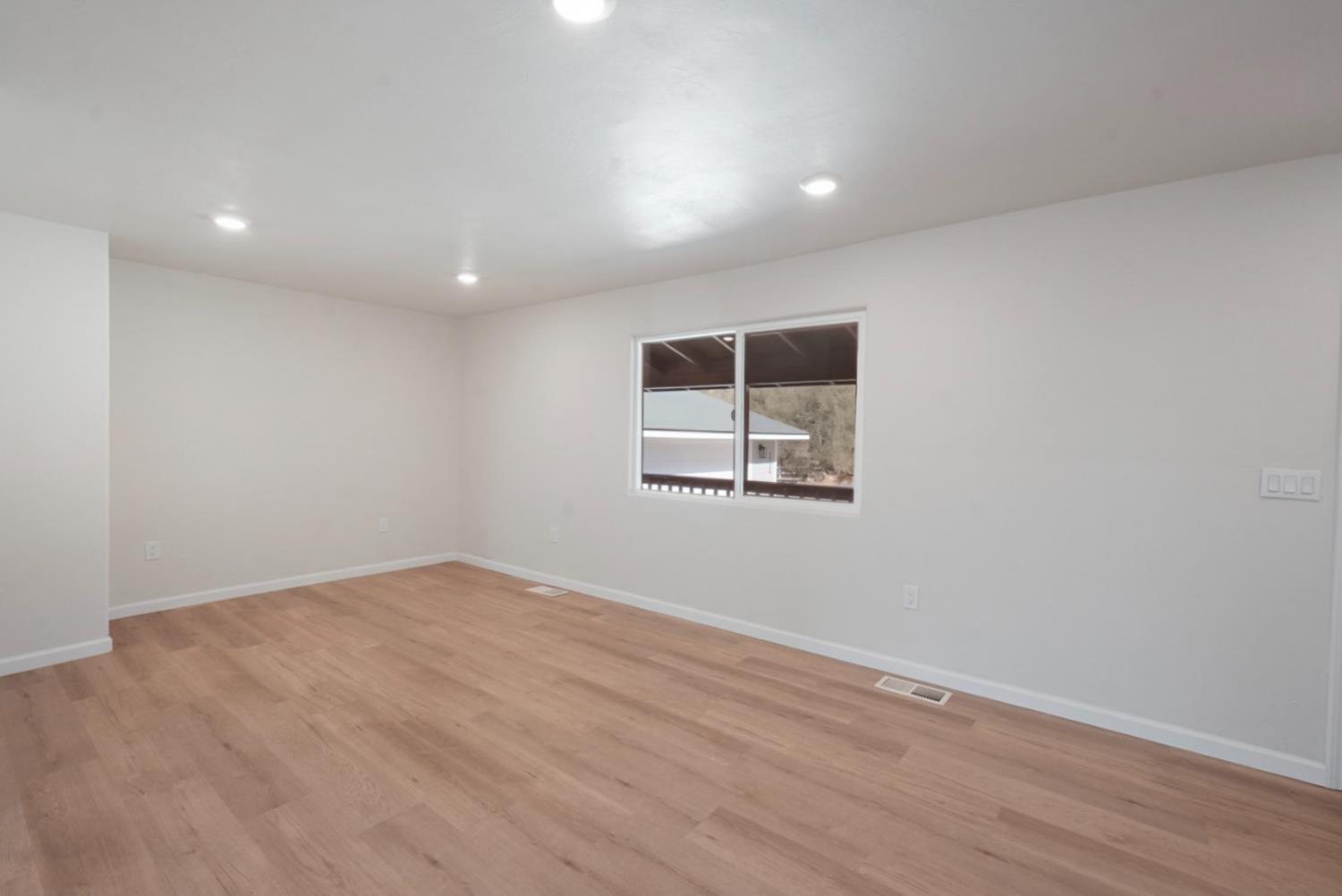 2324 Quail Hill Road Copperopolis, CA 95228 - Photo 8 of 37 an empty room with wooden floor and windows