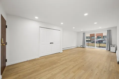a view of an empty room with wooden floor and closet