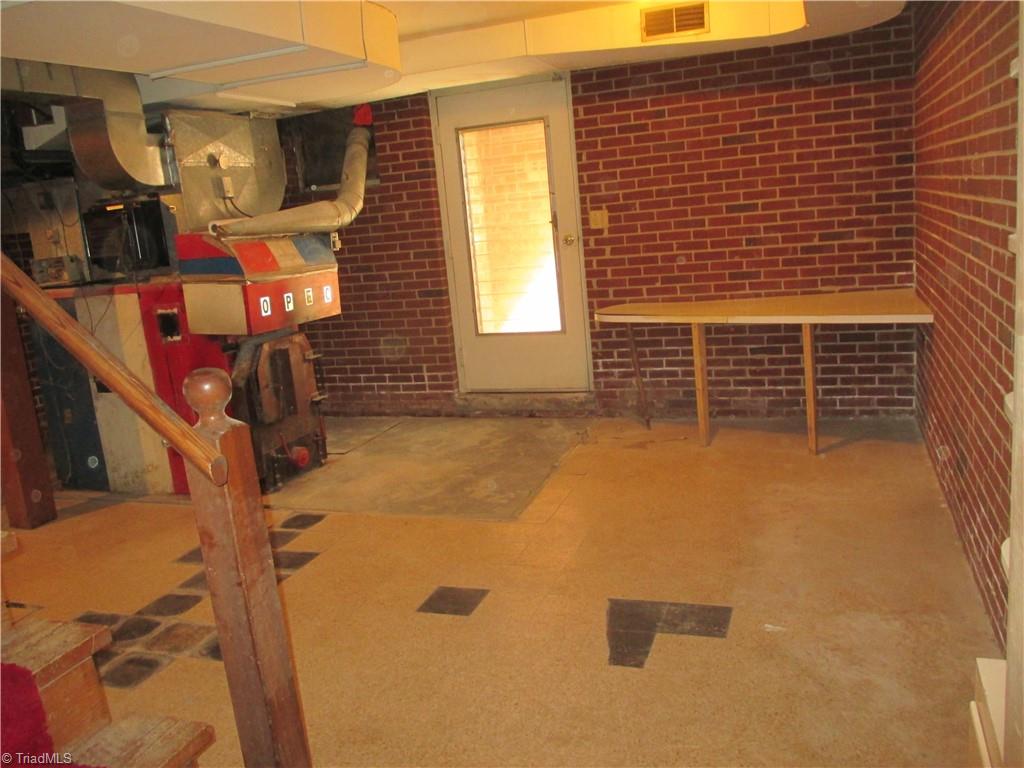 541 Eden Road Stoneville, NC 27048 - Photo 33 of 50 basement room bottom of stairs, door to outside steps, and wood furnacr