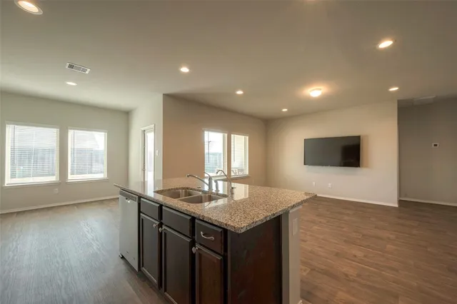 a kitchen with a sink and a stove top oven with wooden floor