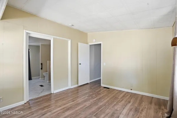 a view of an empty room with wooden floor and closet