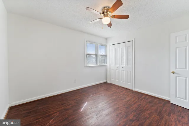 an empty room with wooden floor chandelier fan and windows