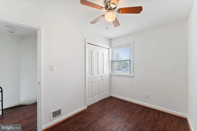 an empty room with wooden floor chandelier fan and windows