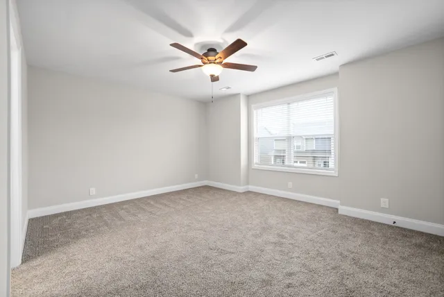 an empty room with windows and fan