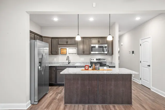 a kitchen with stainless steel appliances a sink a stove a refrigerator cabinets and wooden floor