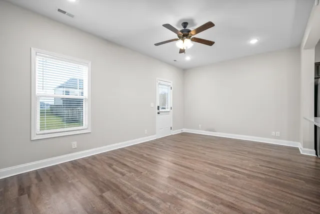 an empty room with wooden floor and windows