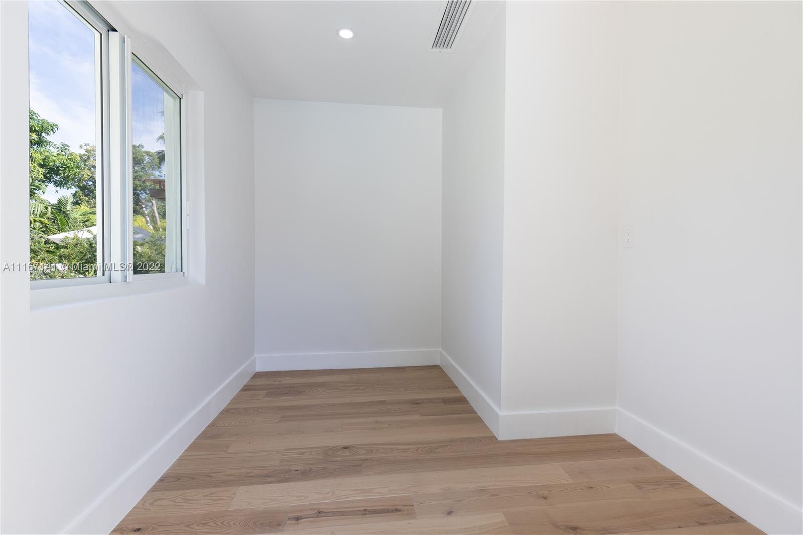 4730 Bay Point Road Miami, FL 33137 - Photo 16 of 25 a view of an empty room with wooden floor and a window