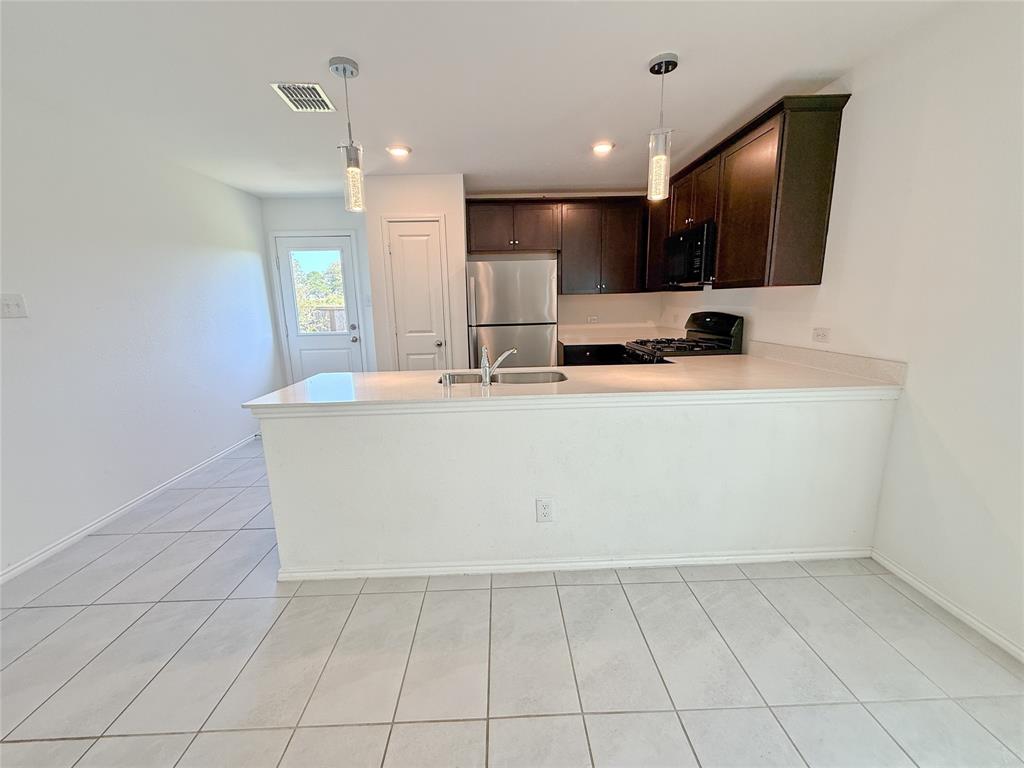 3701 Harper Street Little Elm, TX 75068 - Photo 4 of 26 a view of a kitchen with kitchen island a sink a counter top space and cabinets