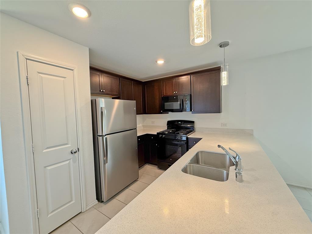 3701 Harper Street Little Elm, TX 75068 - Photo 5 of 26 a kitchen with a refrigerator a sink and cabinets
