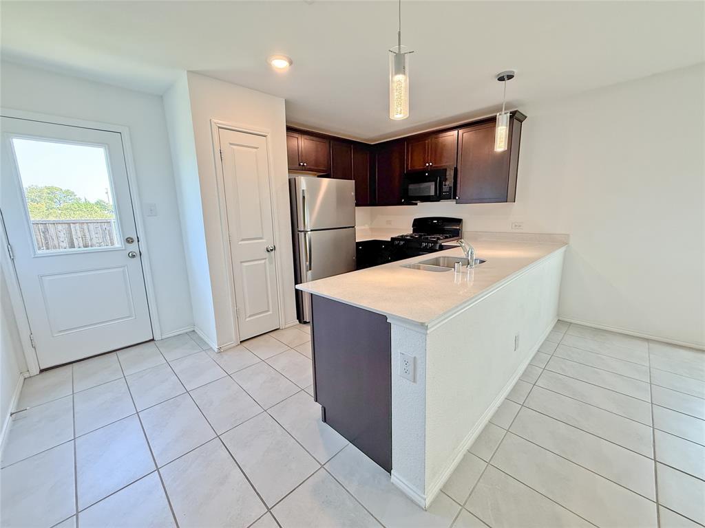 3701 Harper Street Little Elm, TX 75068 - Photo 7 of 26 a kitchen with a sink a refrigerator a microwave and cabinets