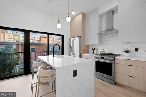 a kitchen with stainless steel appliances granite countertop a stove a sink and a refrigerator with wooden floor