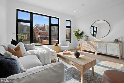 a living room with furniture a lamp a potted plant and a large window