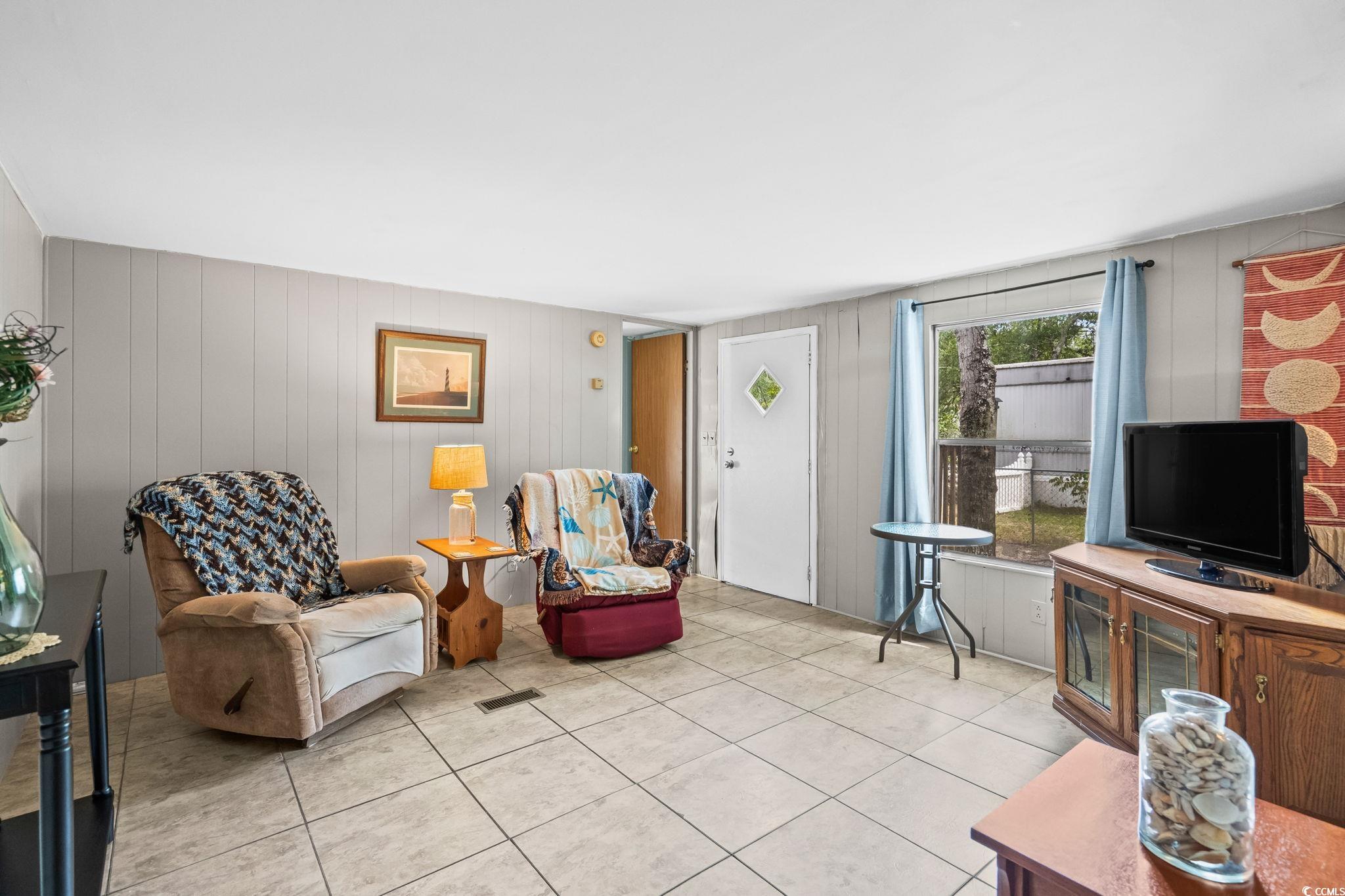 4516 Willet Street North Myrtle Beach, SC 29582 - Photo 12 of 40 Living room featuring light tile patterned floors and wood walls